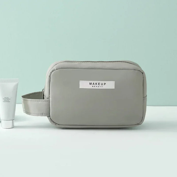 Astuccio da trucco grigio con cerniera, design minimalista, ideale per cosmetici e accessori da viaggio. Elegante e pratico per l'organizzazione.