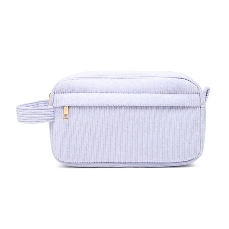 Borsa da toilette in tessuto a coste lilla con cerniera dorata e manico laterale. Elegante e pratica per viaggi e organizzazione bagno.