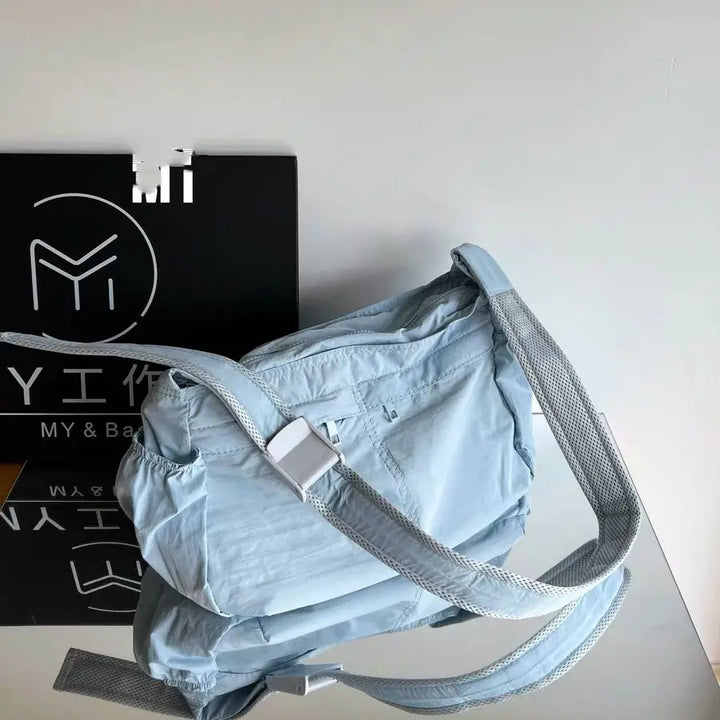 Borsa a tracolla azzurra con cinturino regolabile, design moderno, su sfondo bianco e nero. Accessorio moda versatile per donna.
