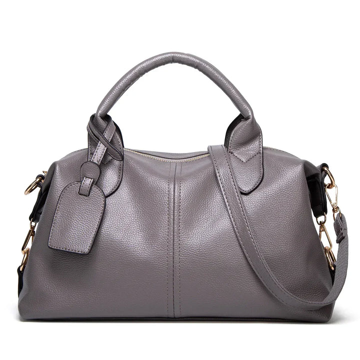 Borsa a mano in pelle grigia con tracolla regolabile, dettagli in metallo dorato e targhetta. Elegante e spaziosa, ideale per ogni occasione.