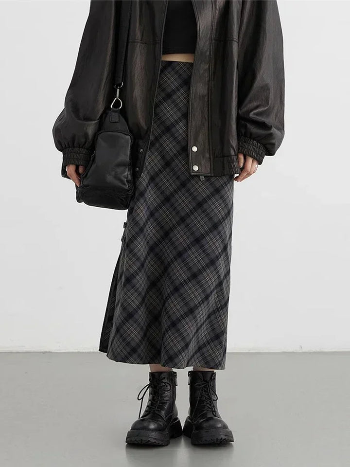 Gonna lunga a quadri grigi, giacca in pelle nera oversize, stivali neri robusti, borsa a tracolla nera. Moda streetwear autunnale donna.