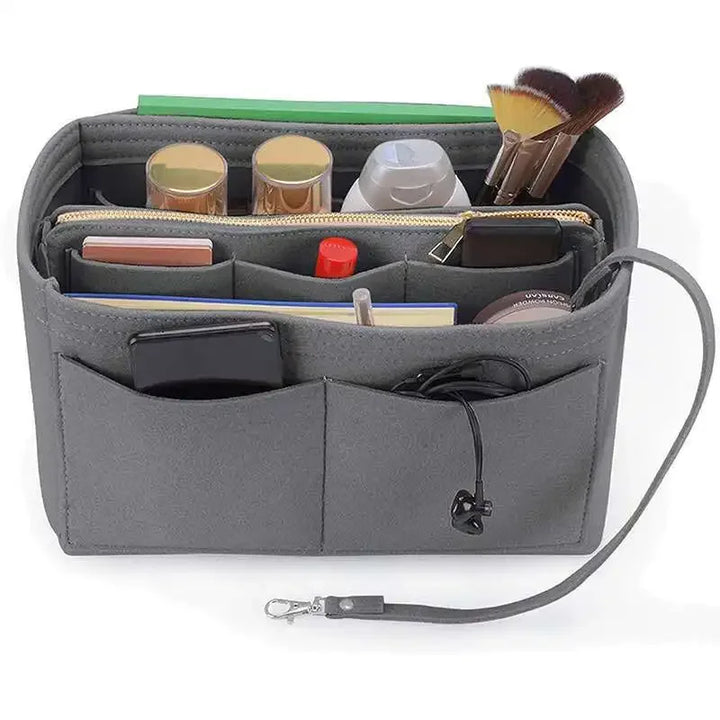 Organizer borsa grigio con tasche multiple, contenente trucchi, pennelli, e accessori. Ideale per organizzare cosmetici e oggetti personali.