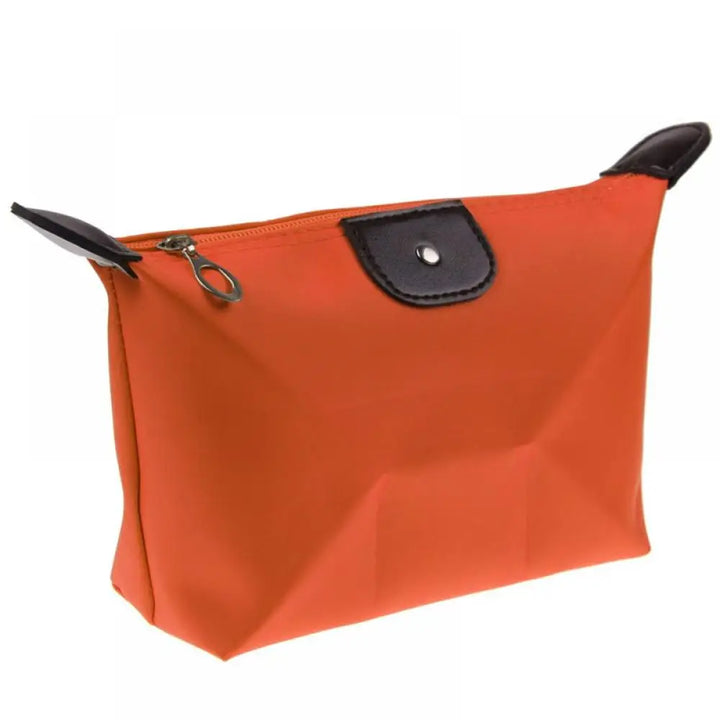 Borsa cosmetica arancione con cerniera, dettagli in pelle nera, design elegante e compatto, ideale per viaggio e organizzazione trucco.