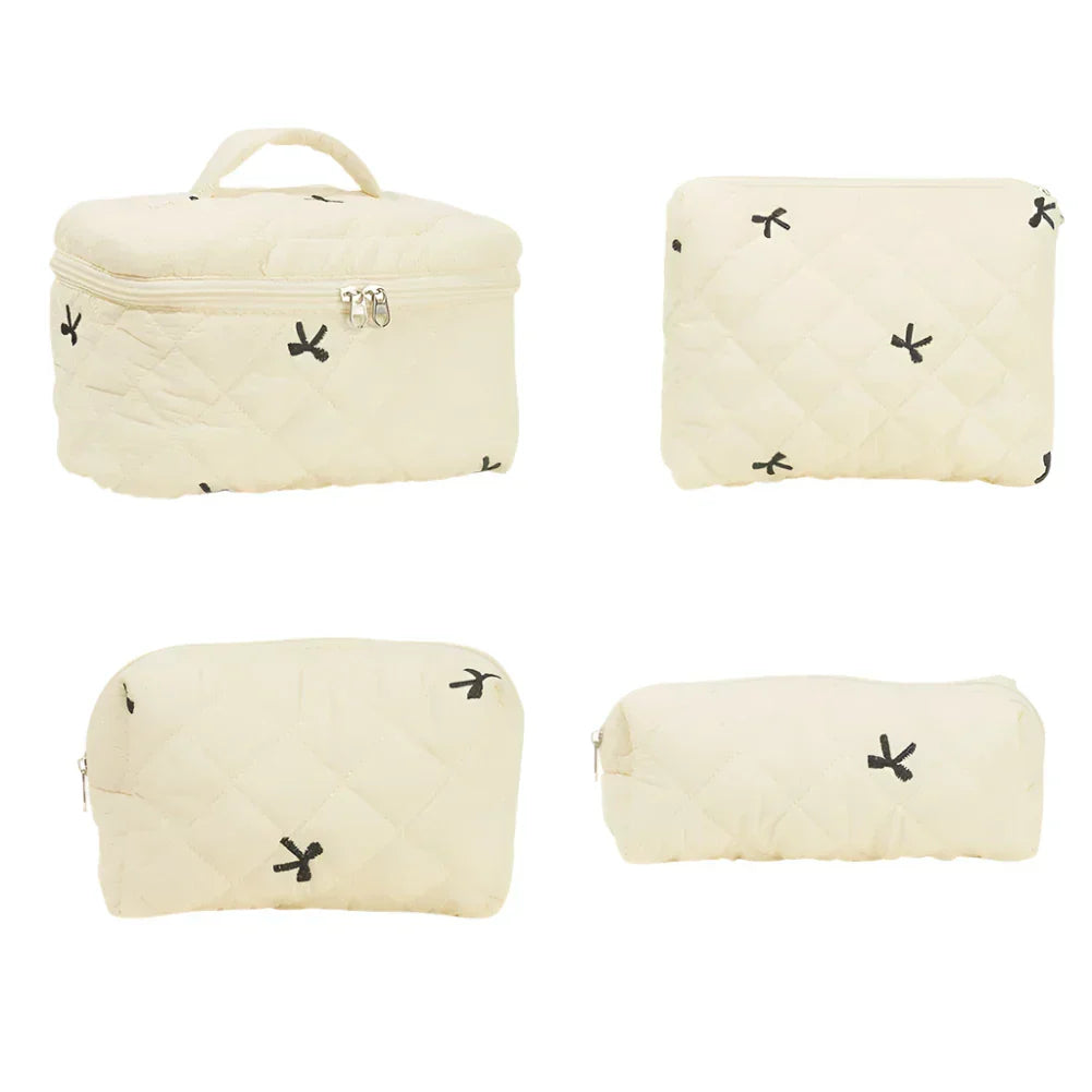 Set di quattro borse da viaggio beige trapuntate con cerniera, design minimalista con piccoli motivi neri. Ideale per organizzare cosmetici e accessori.