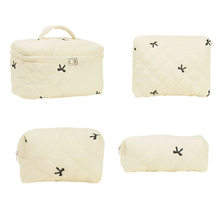 Set di quattro borse da viaggio beige trapuntate con cerniera, design minimalista con piccoli motivi neri. Ideale per organizzare cosmetici e accessori.