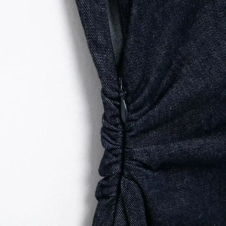 Vestito nero in denim con arricciature laterali, chiusura a zip nascosta. Elegante e moderno, perfetto per occasioni casual e serali.