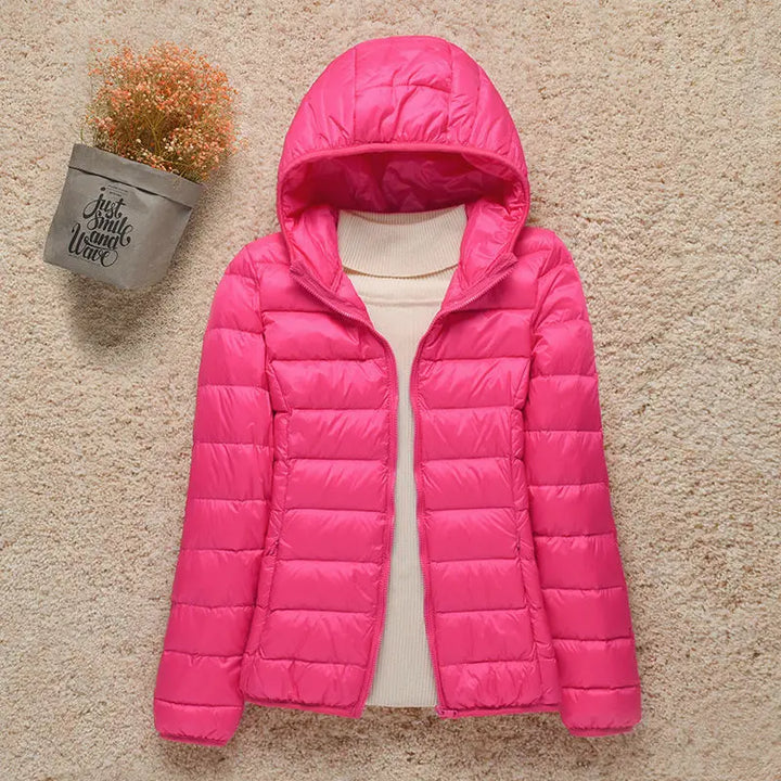 Giacca invernale rosa con cappuccio, imbottita, su sfondo beige. Moda donna, abbigliamento caldo, stile casual. Perfetta per l'inverno.