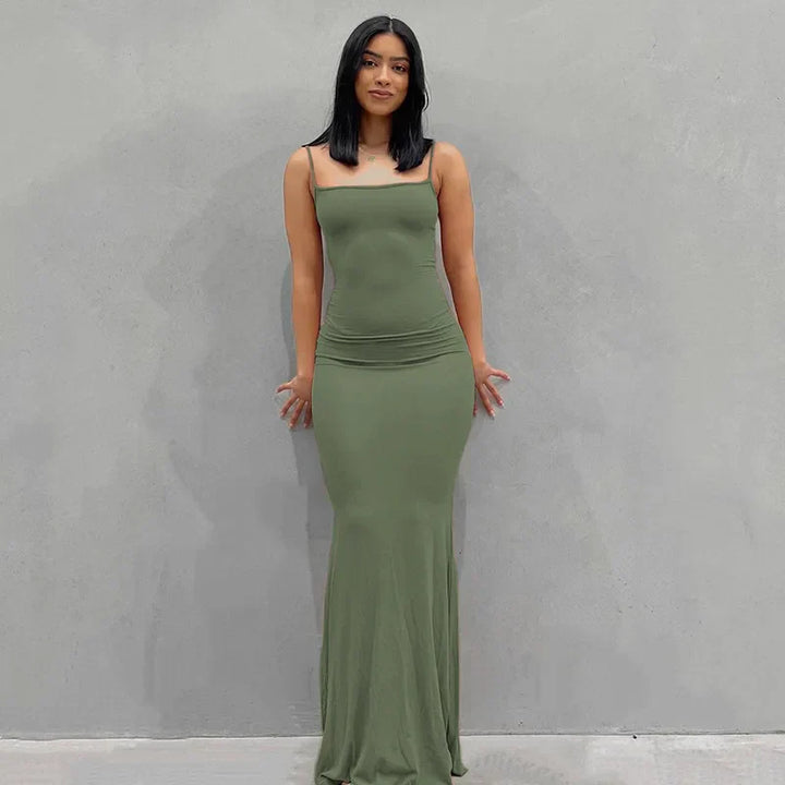 Abito lungo verde oliva aderente, senza maniche, indossato da una donna su sfondo grigio. Elegante e moderno, perfetto per eventi serali.