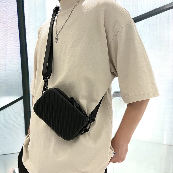 Borsa a tracolla nera unisex, design moderno e compatto, indossata su maglietta beige. Accessorio moda casual, ideale per ogni occasione.