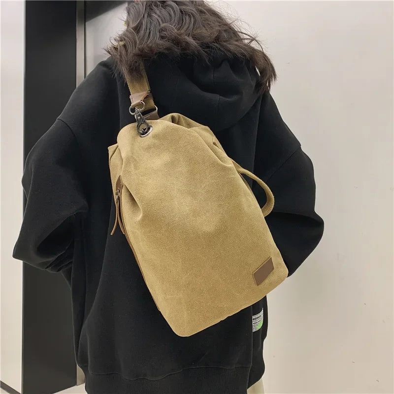 Zaino in tela beige su persona con felpa nera, design casual e moderno, ideale per scuola o viaggio. Accessorio moda unisex, resistente e capiente.