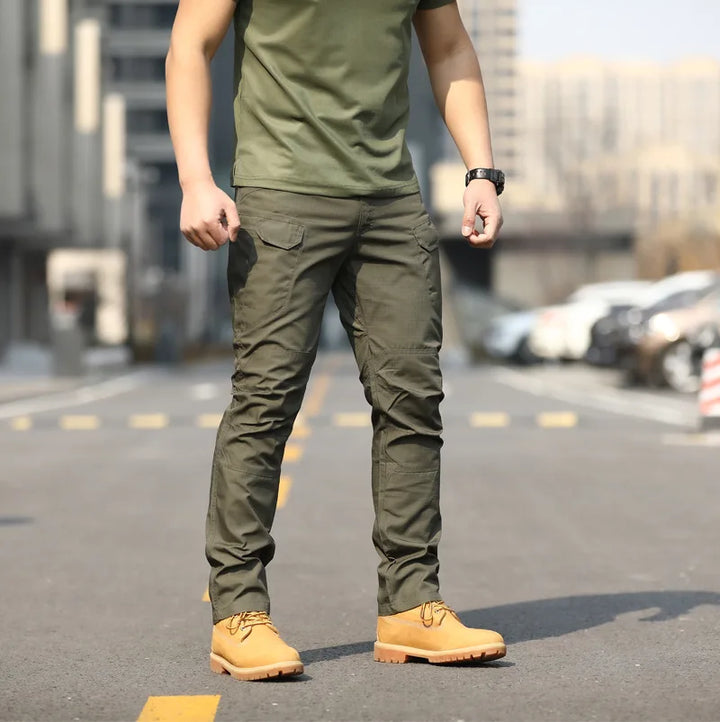 Uomo in pantaloni cargo verdi e stivali gialli su strada urbana. Moda casual maschile, abbigliamento outdoor, stile militare.