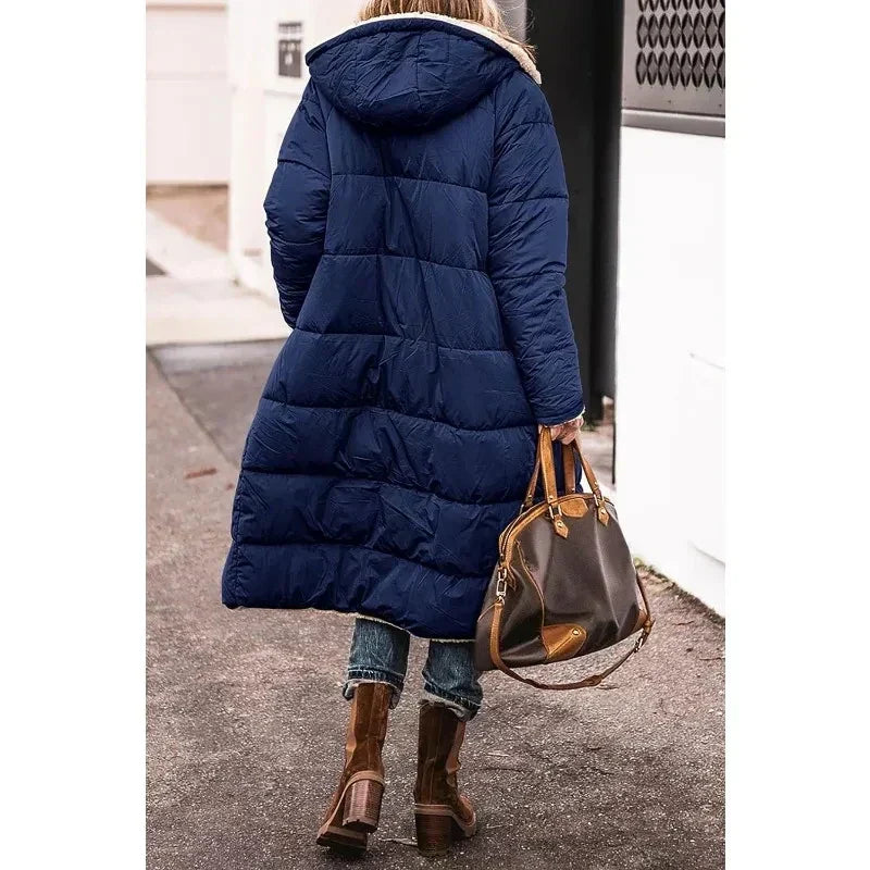 Donna con cappotto lungo blu, stivali marroni e borsa in pelle. Moda invernale, abbigliamento casual, passeggiata urbana.