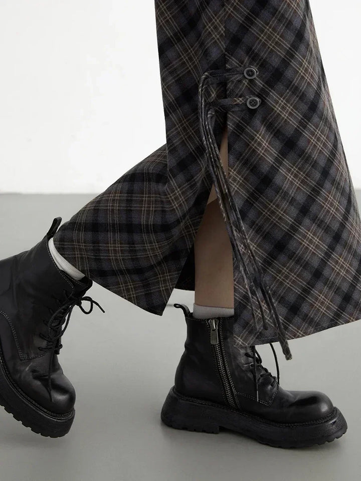 Pantaloni a quadri con lacci laterali, abbinati a stivali neri in pelle con cerniera. Moda autunnale, stile casual chic.