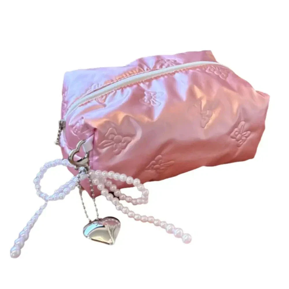 Astuccio rosa in raso con cerniera, decorato con motivi floreali, perline e ciondolo a cuore. Accessorio moda elegante e funzionale.