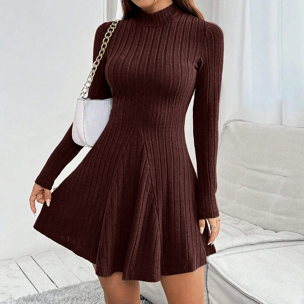 Vestito maglione marrone a coste, maniche lunghe, scollo alto, abbinato a borsa bianca a tracolla. Elegante abbigliamento autunnale da donna.