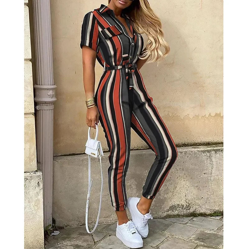 Tuta a righe verticali multicolore, maniche corte, cintura in vita, abbinata a sneakers bianche e borsa a mano bianca. Moda donna casual chic.