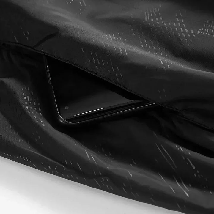 Smartphone nero in tasca di giacca impermeabile nera, design elegante e moderno, accessorio tecnologico, moda outdoor, protezione dispositivo.