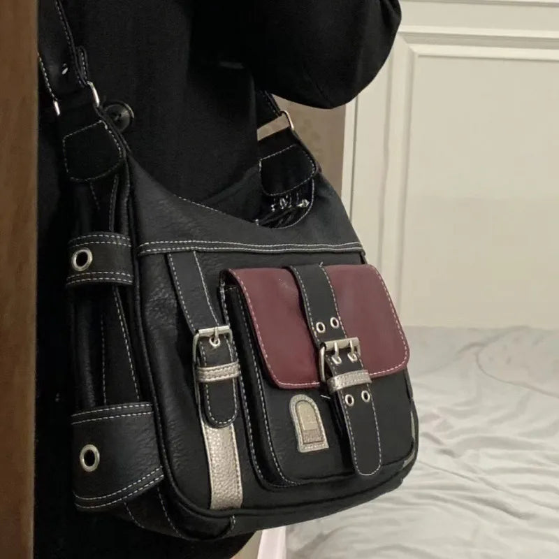 Borsa a tracolla nera con dettagli in metallo e tasca frontale bordeaux, design elegante e moderno, perfetta per moda urbana e casual.