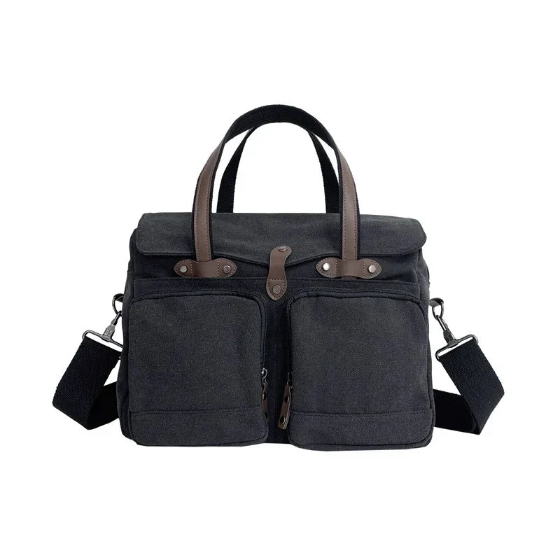 Borsa a tracolla in tela nera con manici marroni, doppie tasche frontali e tracolla regolabile. Design elegante e funzionale per uomo e donna.