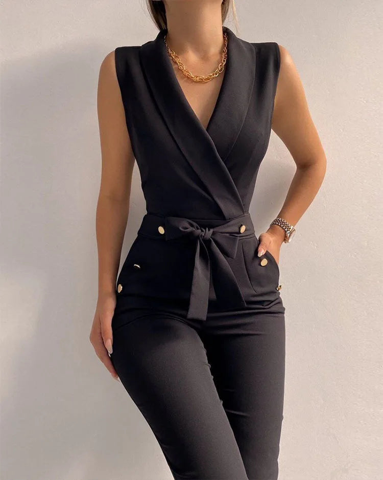 Tuta elegante nera senza maniche, con cintura in vita e bottoni dorati, indossata da una donna. Abbigliamento moda donna, stile sofisticato.