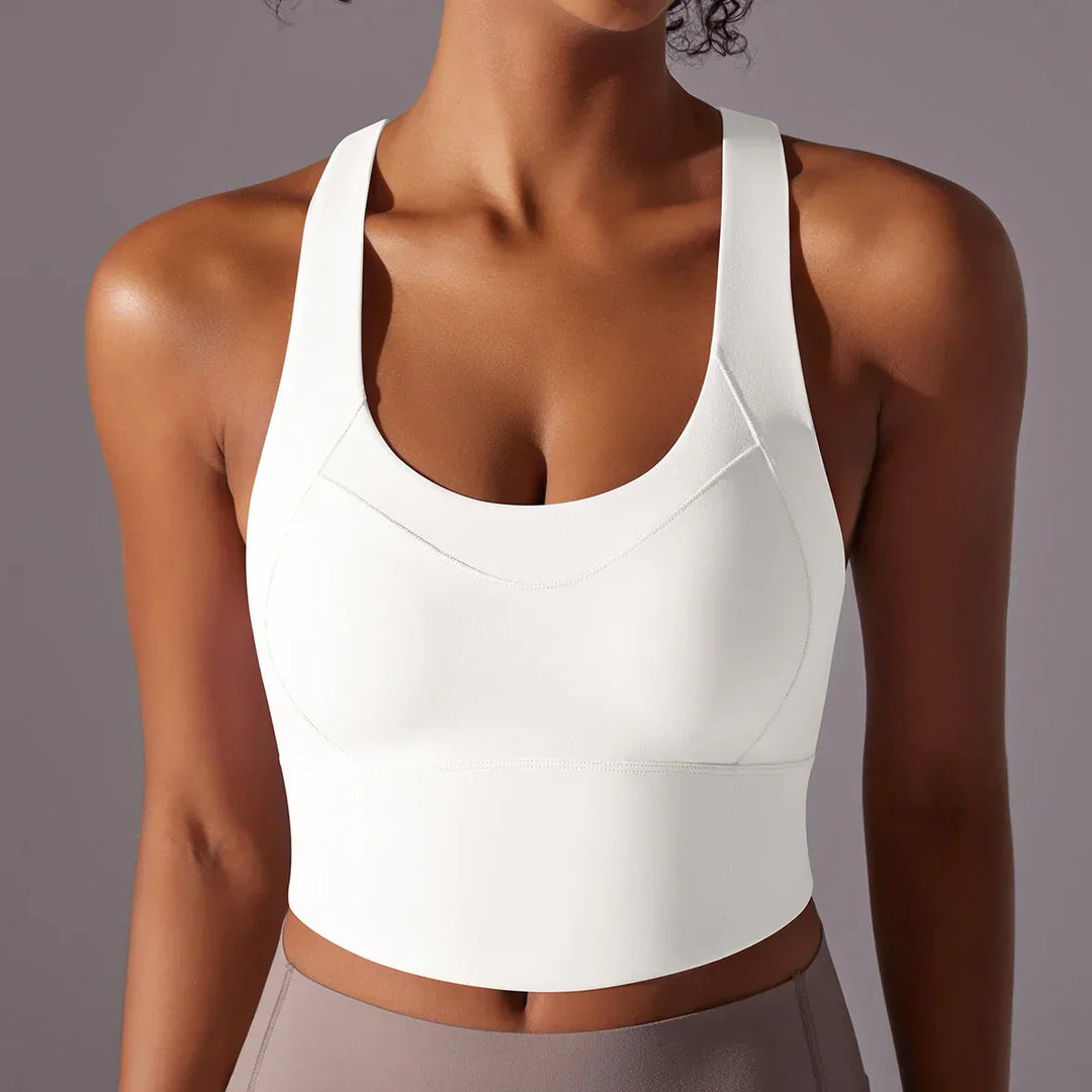 Top sportivo bianco da donna, senza maniche, con scollo a U, indossato su sfondo grigio. Ideale per yoga, fitness e allenamento.