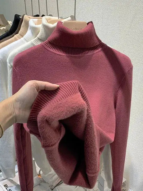 Maglione dolcevita rosa in lana, esposto su appendiabiti, con dettagli a coste. Moda autunnale, abbigliamento donna elegante e caldo.