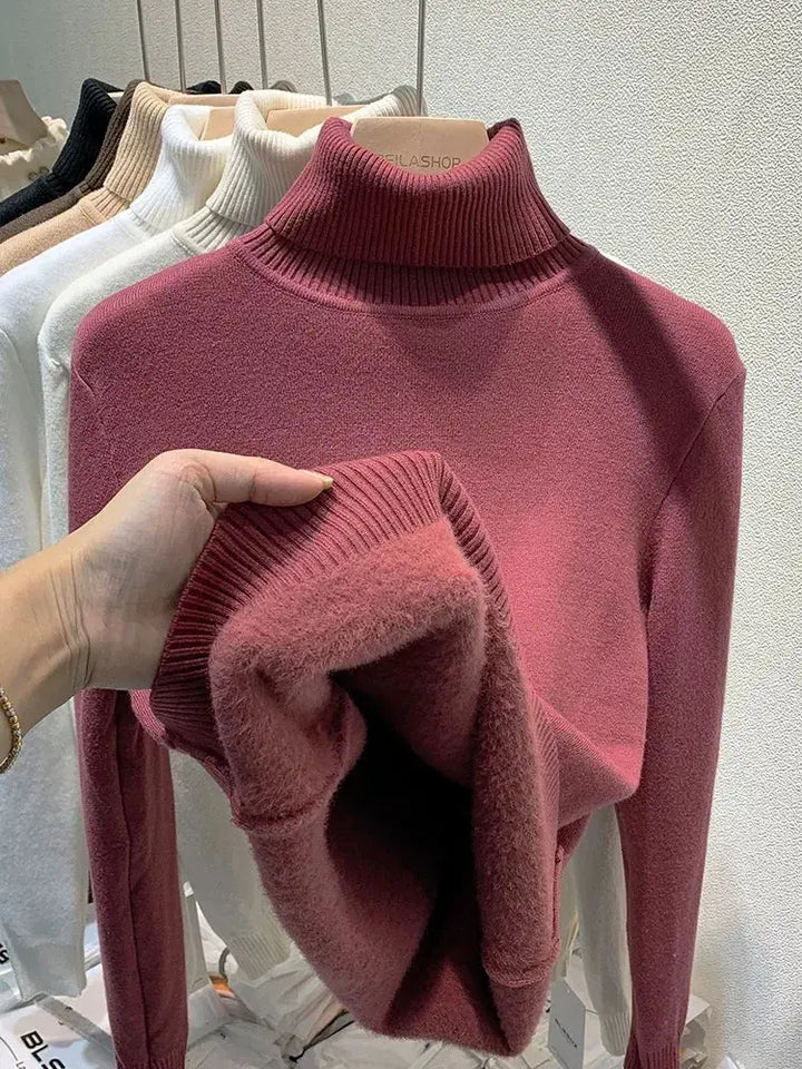 Maglione dolcevita rosa in lana morbida, esposto su appendiabiti con altri colori. Moda autunnale, abbigliamento caldo, stile casual elegante.