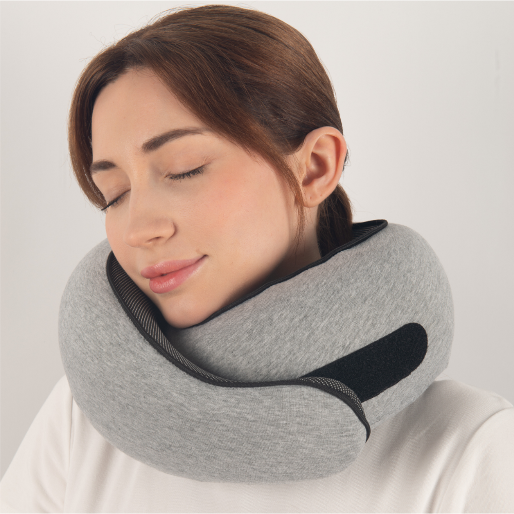 Donna con cuscino da viaggio ergonomico grigio, supporto collo, comfort in viaggio, accessorio per aereo, relax e riposo, design moderno.