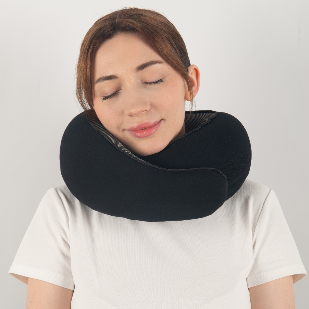 Donna con cuscino da viaggio nero, ergonomico, supporto collo, comfort, relax, ideale per viaggi in aereo, auto, treno. Accessorio viaggio essenziale.