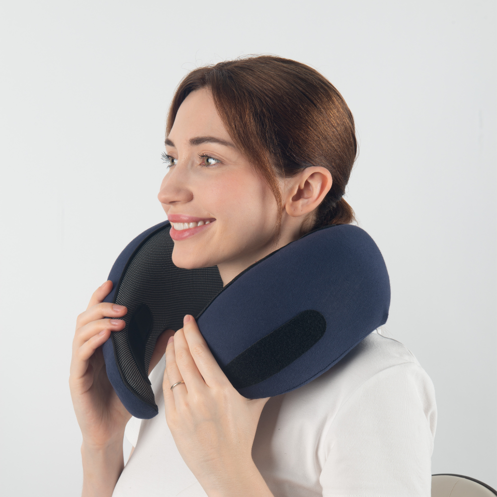 Donna sorridente con cuscino da viaggio per il collo blu, ergonomico e regolabile. Accessorio ideale per comfort in aereo, auto o treno.