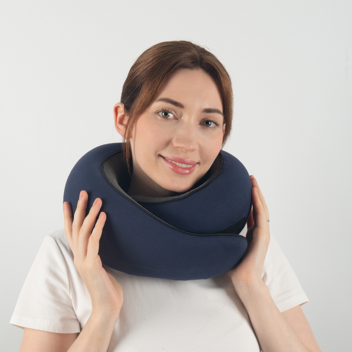 Donna con cuscino da viaggio ergonomico blu, supporto collo, comfort in viaggio, accessorio essenziale per aereo, auto, treno.
