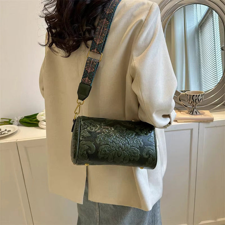 Borsa a tracolla verde scuro in pelle con motivo floreale, indossata su giacca beige. Accessorio moda elegante per donna, perfetto per ogni occasione.