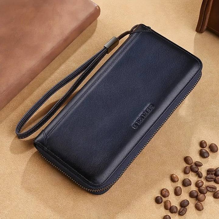 Portafoglio uomo in pelle nera con cerniera, cinturino da polso, su sfondo beige con chicchi di caffè. Elegante accessorio moda maschile.