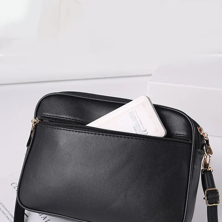 Borsa a tracolla in pelle nera con tasca frontale, chiusura a zip e dettagli dorati. Design elegante e pratico per uso quotidiano.