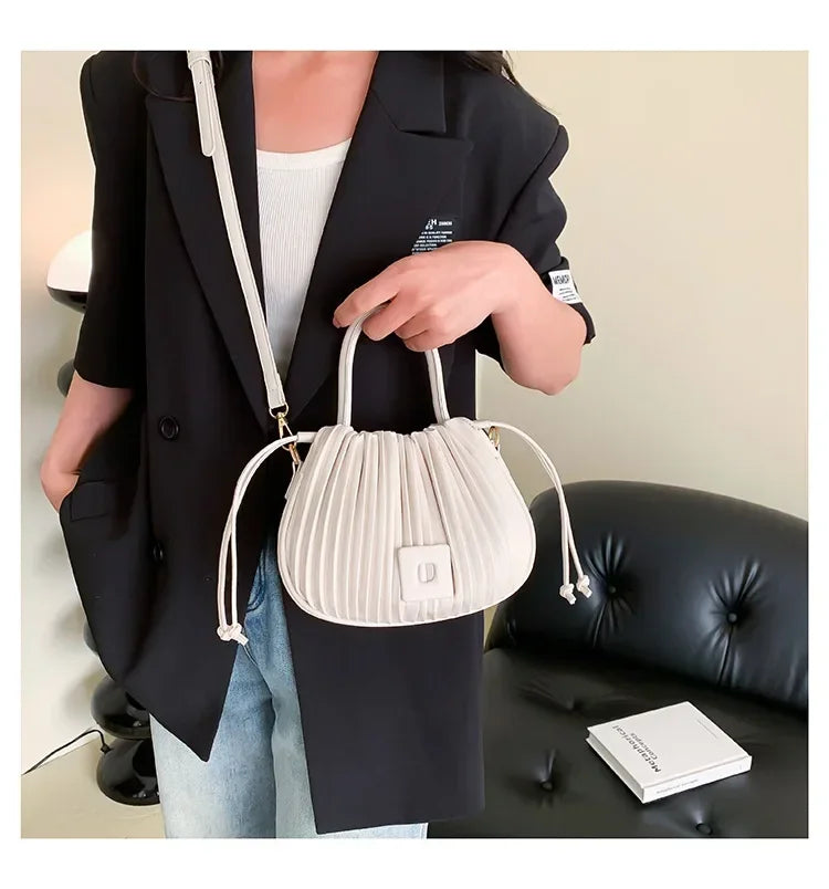 Borsa a mano bianca plissettata, indossata con blazer nero e jeans. Elegante accessorio moda donna, perfetto per look casual-chic.