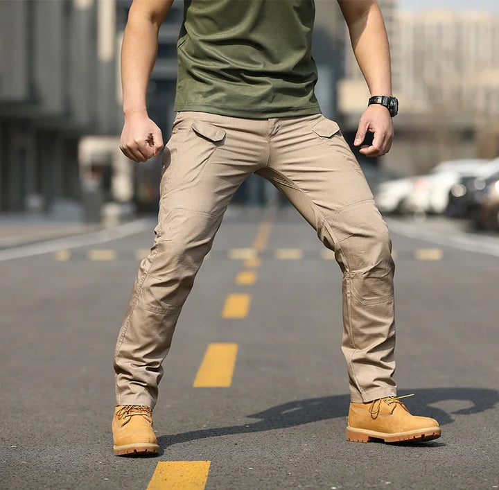 Uomo in strada indossa pantaloni cargo beige, maglietta verde e stivali gialli. Moda urbana, abbigliamento casual maschile, stile outdoor.