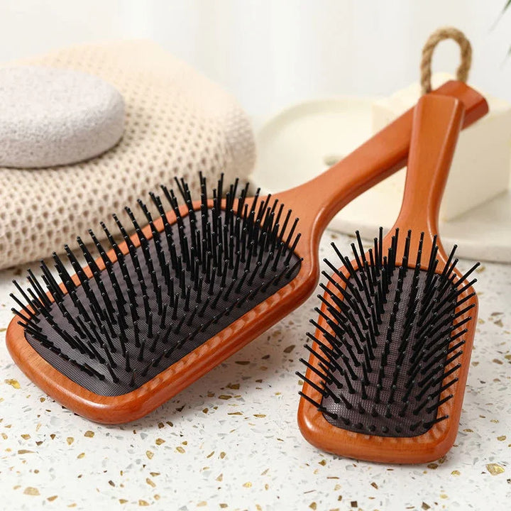 Due spazzole per capelli in legno con setole nere su sfondo chiaro. Accessori per la cura dei capelli, ideali per districare e lisciare.