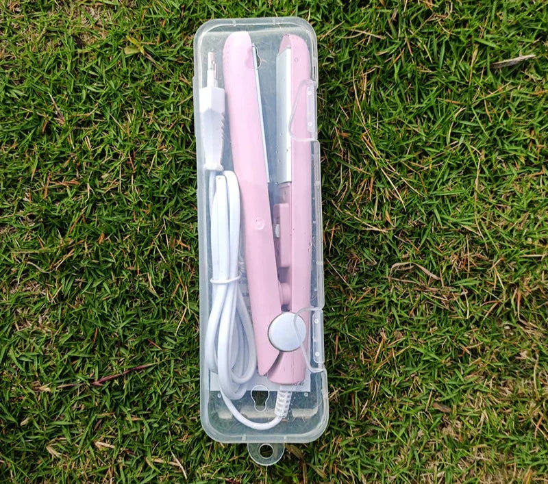 Piastra per capelli rosa portatile in custodia trasparente su erba verde, con cavo USB. Ideale per styling capelli in viaggio.