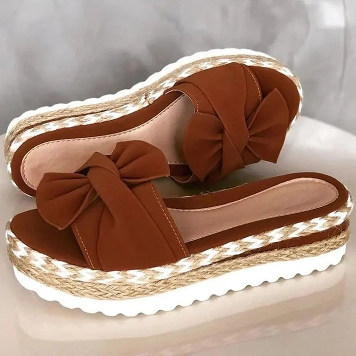 Sandali donna marroni con zeppa in corda, fiocco decorativo, suola bianca ondulata. Scarpe estive eleganti, moda casual, comode e trendy.
