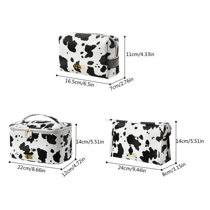 Set di tre beauty case in pelle sintetica con stampa mucca bianco e nero, dimensioni varie, chiusura a zip, ideale per viaggio e organizzazione cosmetici.