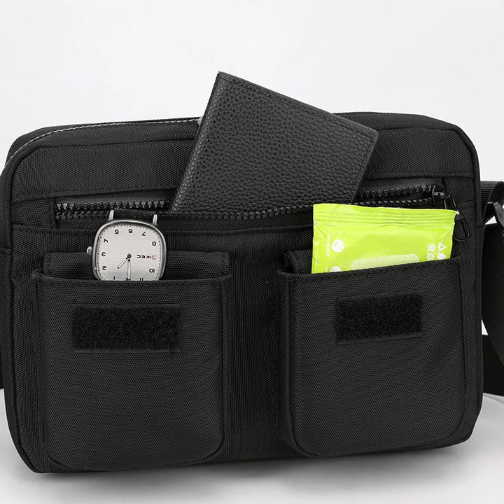 Borsa a tracolla nera con tasche multiple, orologio, portafoglio e pacchetto verde. Accessorio moda uomo, pratico e versatile.