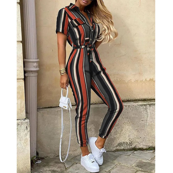 Tuta a righe verticali nere, rosse e beige, con cintura in vita. Donna con borsa bianca e scarpe da ginnastica. Moda casual elegante.