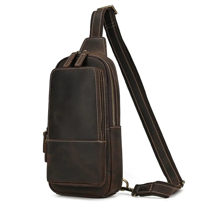 Zaino monospalla in pelle marrone scuro, design elegante e compatto, con cerniere dorate e tracolla regolabile. Ideale per uomo e donna.