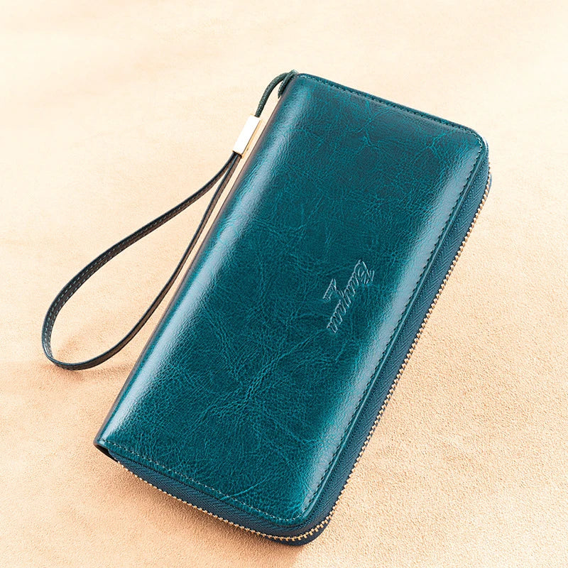 Portafoglio in pelle verde scuro con cerniera, cinturino da polso e logo inciso. Accessorio elegante per uomo e donna, ideale per regali.