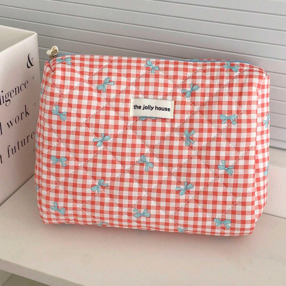 Astuccio trapuntato a quadretti rossi e bianchi con fiocchi blu, etichetta "the jolly house". Accessorio moda, organizer da viaggio elegante.
