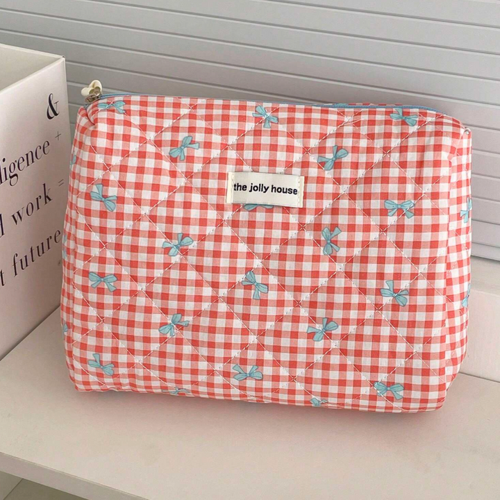 Astuccio trapuntato a quadretti rossi e bianchi con fiocchi blu, etichetta "the jolly house". Accessorio moda, organizer da viaggio elegante.