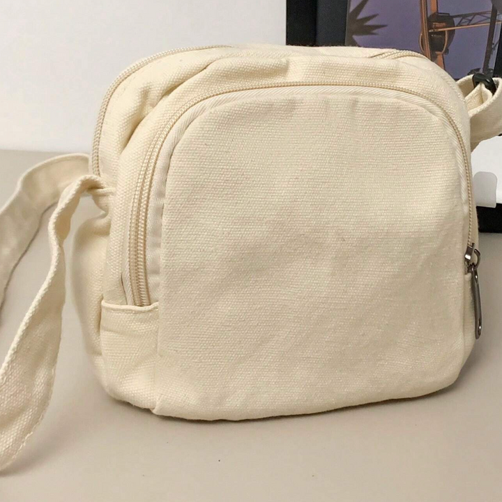 Borsa a tracolla in tela beige, design compatto con cerniera, ideale per uso quotidiano. Accessorio moda pratico e versatile.