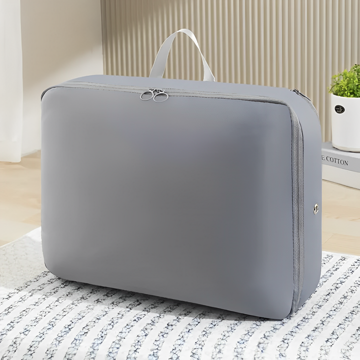 Valigia organizer grigia con manico, design compatto e moderno, ideale per viaggi e organizzazione, posizionata su un letto in una stanza luminosa.