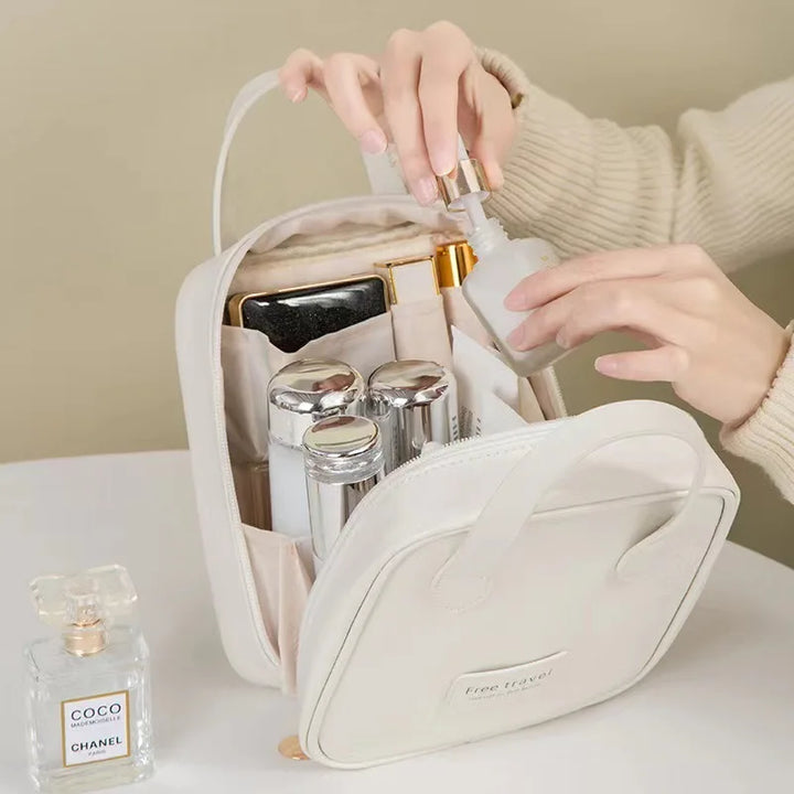 Borsa da viaggio bianca con flaconi cosmetici, profumo Chanel e mani femminili. Organizer cosmetici, accessori viaggio, beauty case elegante.
