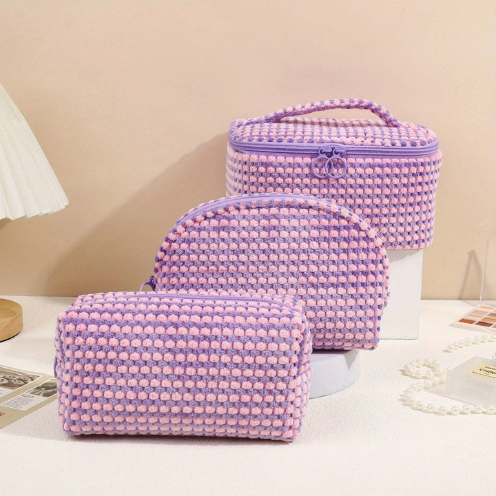 Set di tre borse da trucco in tessuto lavorato a maglia rosa e viola, con cerniera e manico, ideali per cosmetici e accessori da viaggio.
